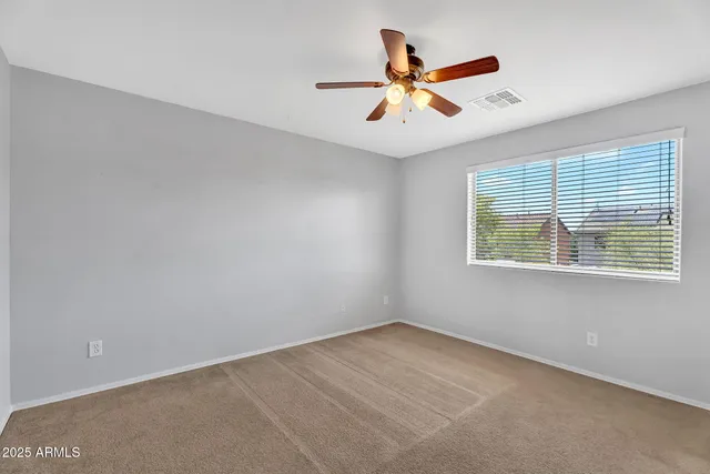 an empty room with ceiling fan and window