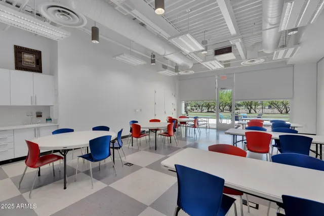 a room with lots of tables a large window and chairs