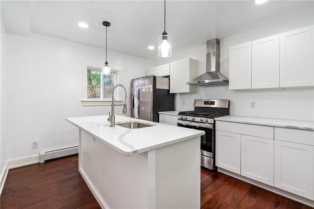 8619 Westwood Road Pittsburgh, PA 15235 - Photo 11 of 26 a kitchen with stainless steel appliances granite countertop a sink a stove a refrigerator and island with wooden floor
