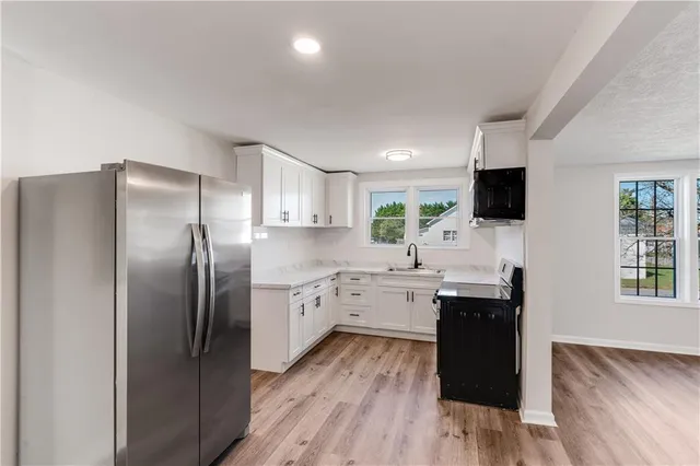 a kitchen with stainless steel appliances granite countertop a refrigerator a sink dishwasher a stove with wooden cabinets and wooden floor