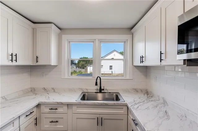 a kitchen with white cabinets and sink