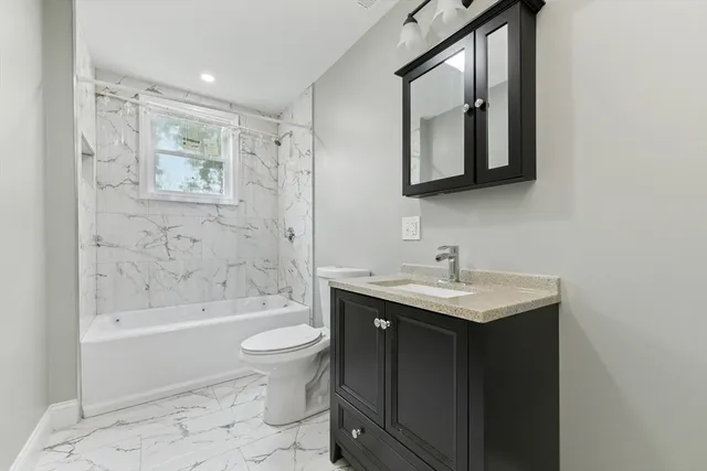 a bathroom with a bathtub shower sink mirror and toilet