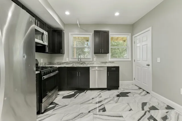 a kitchen with stainless steel appliances kitchen island granite countertop a sink stove and refrigerator