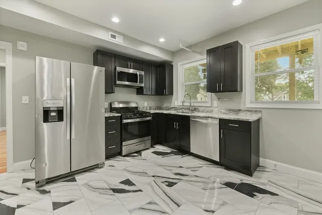 a kitchen with stainless steel appliances kitchen island granite countertop a refrigerator and a sink