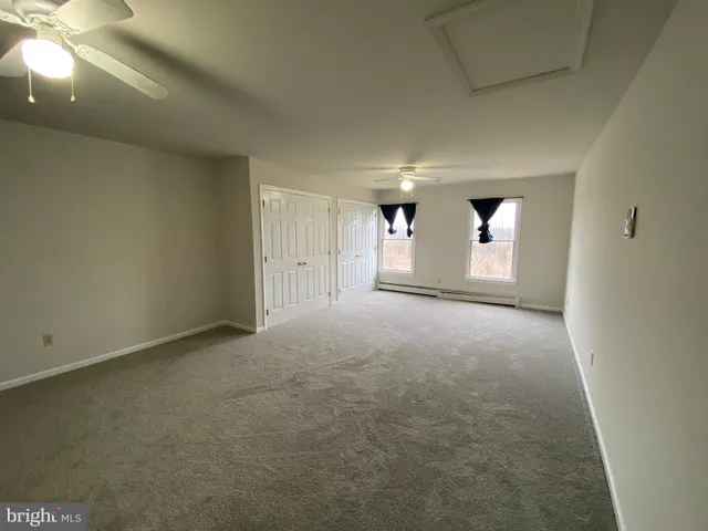 an empty room with windows and fan