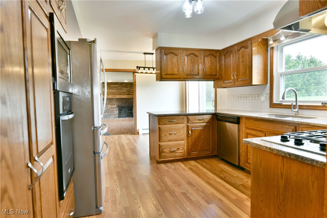 2153 Stillwagon Road Southeast Warren, OH 44484 - Photo 14 of 50 Kitchen featuring stainless steel appliances, brown cabinets, a sink, a peninsula, and light wood finished floors