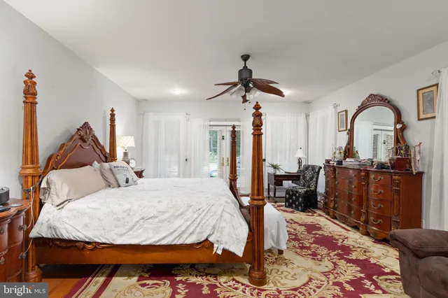 a bedroom with a bed a dresser and wooden floor