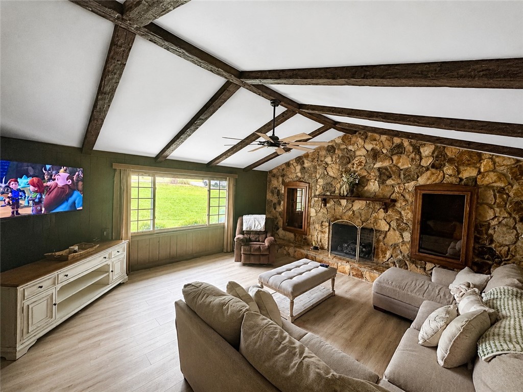 307 Mar-Mac Road Anderson, SC 29626 - Photo 4 of 19 A spacious living room features exposed beam ceilings, a stone fireplace, and light wood flooring.