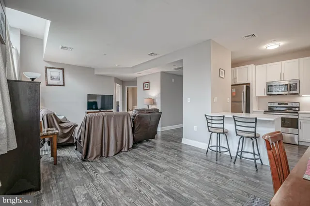 a living room with furniture a flat screen tv and a refrigerator