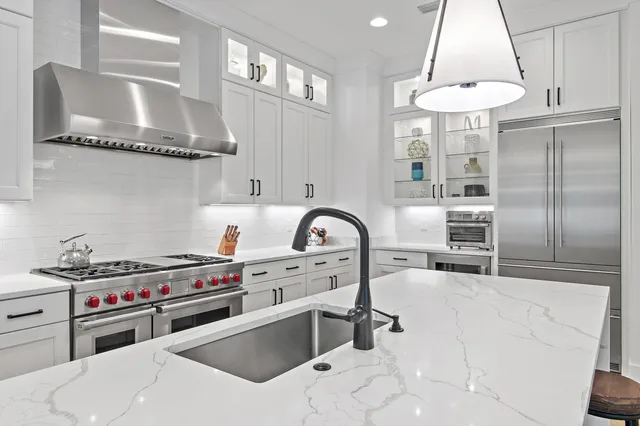 a kitchen with a stove a sink a chandelier and a view of living room