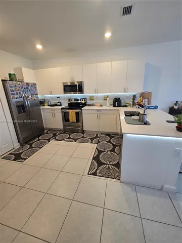 a room with a table chairs and a kitchen view