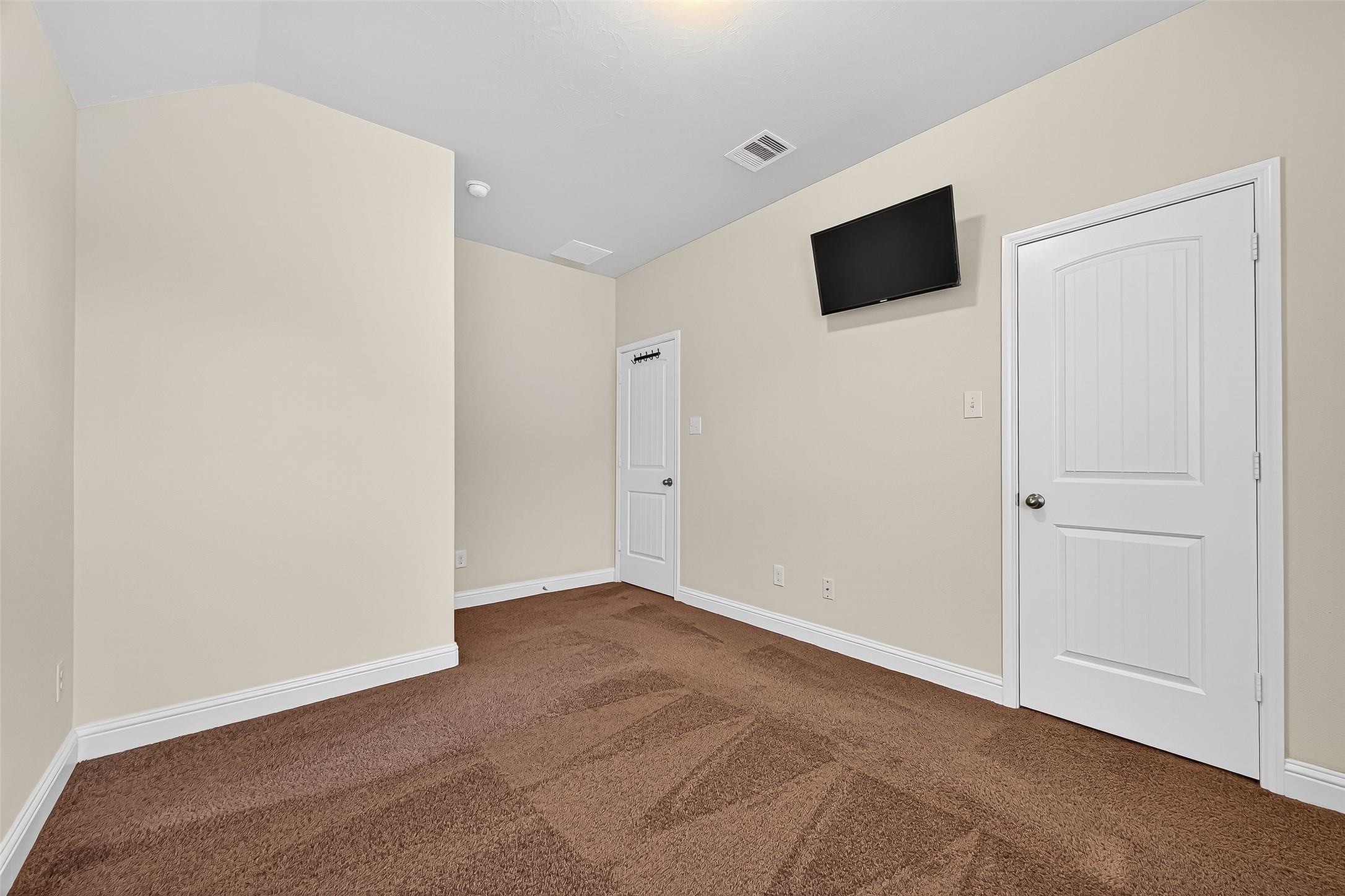 8107 Lockridge Terrace Lane Cypress, TX 77433 - Photo 44 of 50 Another view of the spacious upstairs secondary bedroom highlights its smart layout, high ceilings, and walk-in closet. The mounted TV setup and ample wall space offer versatility for relaxation or productivity. A serene space ready for your personal touch.
