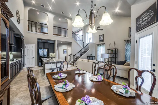 a dining room with lots of furniture chandelier and kitchen view