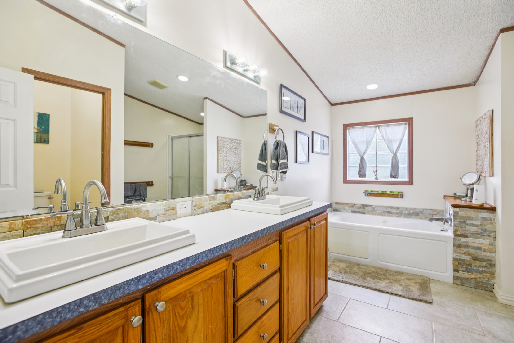 372 Hofferek Road Rosanky, TX 78953 - Photo 17 of 40 Full bath featuring double vanity, a bath, crown molding, light tile patterned floors, and a shower stall