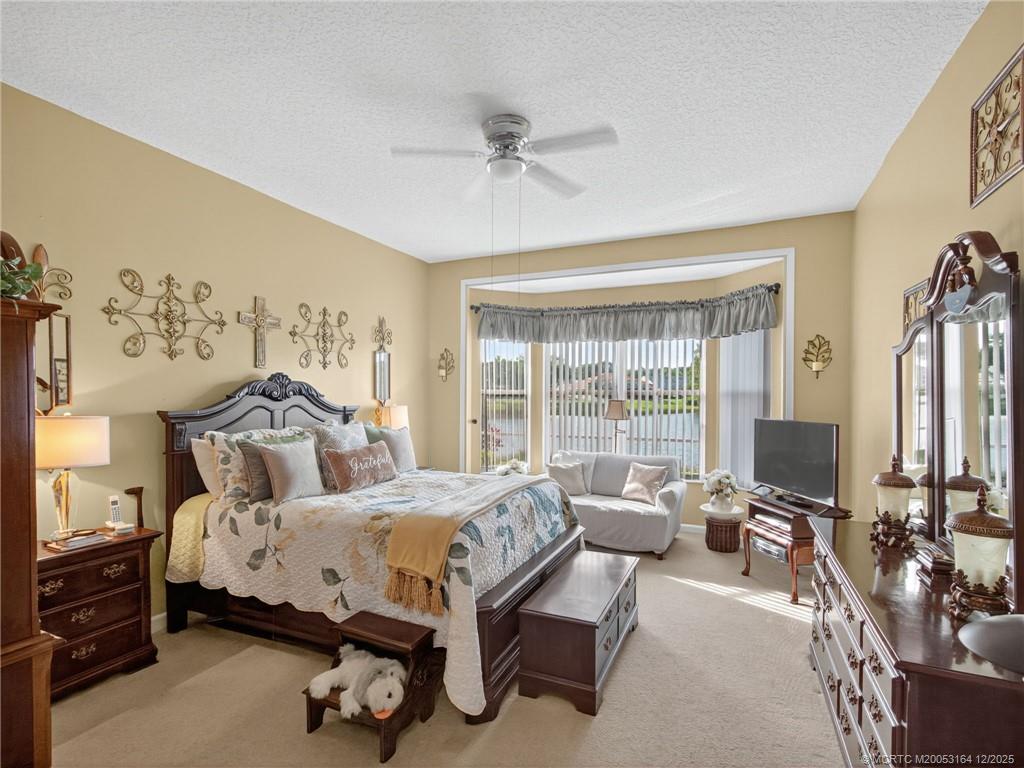 618 Southwest Lake Charles Circle Port St. Lucie, FL 34986 - Photo 15 of 29 a spacious bedroom with a bed a couch and a window