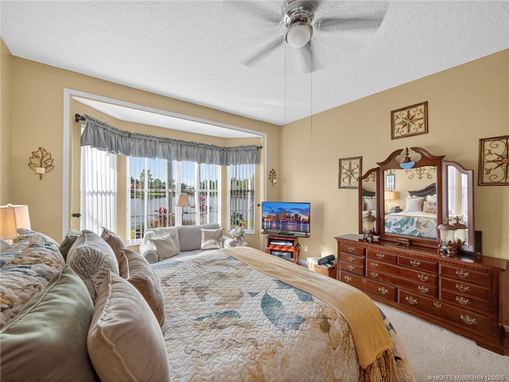 618 Southwest Lake Charles Circle Port St. Lucie, FL 34986 - Photo 16 of 29 a spacious bedroom with a bed a dresser and a flat screen tv