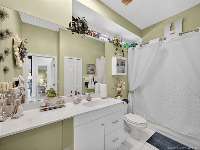 a bathroom with a sink a toilet a mirror a vanity and shower