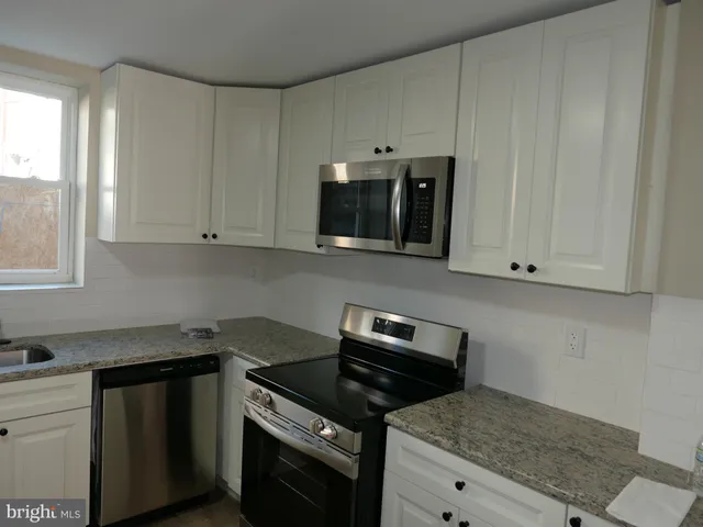 a kitchen with granite countertop white cabinets and black appliances