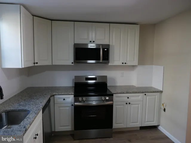 a kitchen with granite countertop a sink and a stove top oven