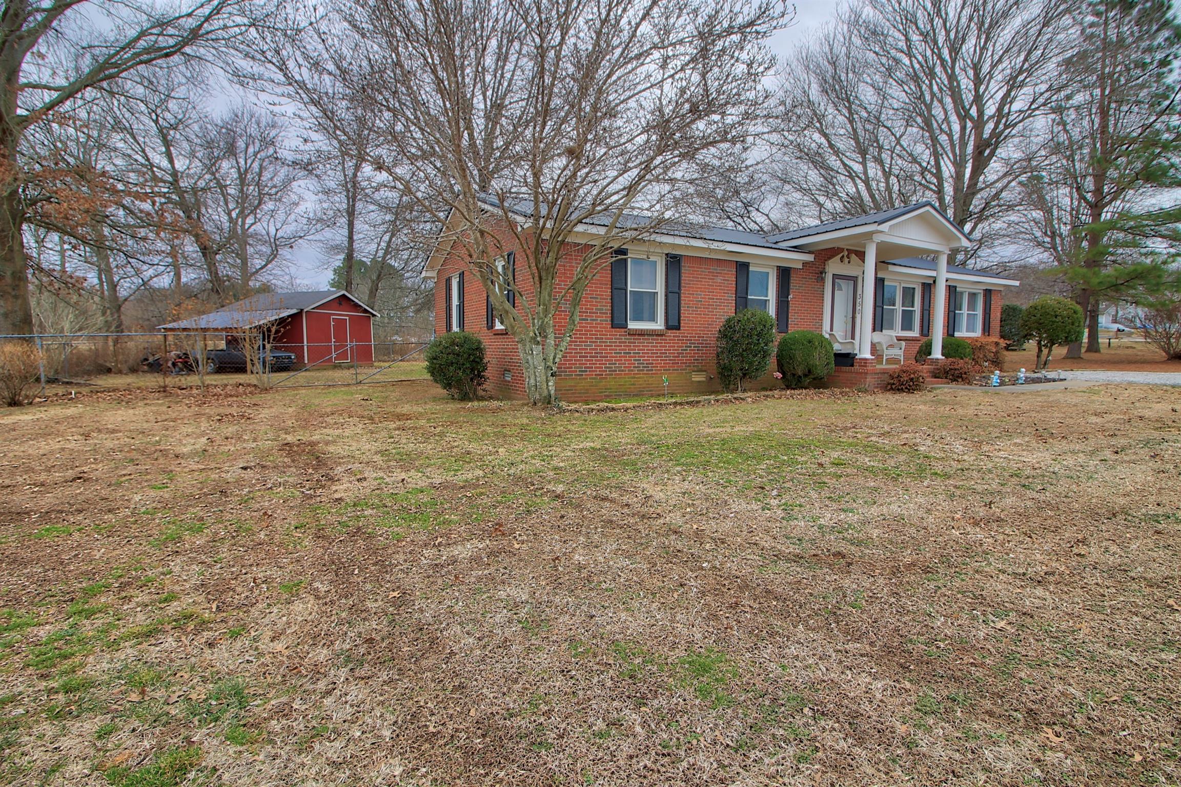 350 Jim Courtney Road Portland, TN 37148 - Photo 2 of 16 a front view of a house with a yard covered with trees