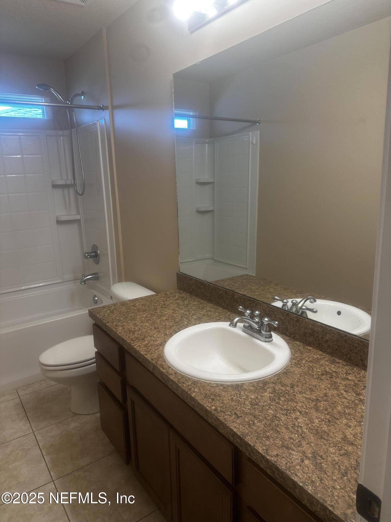 45157 Ingleham Circle Callahan, FL 32011 - Photo 37 of 48 a bathroom with a granite countertop sink a toilet a mirror and bathtub