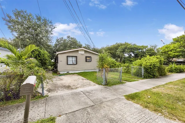 a backyard of a house with table and chairs under an umbrella
