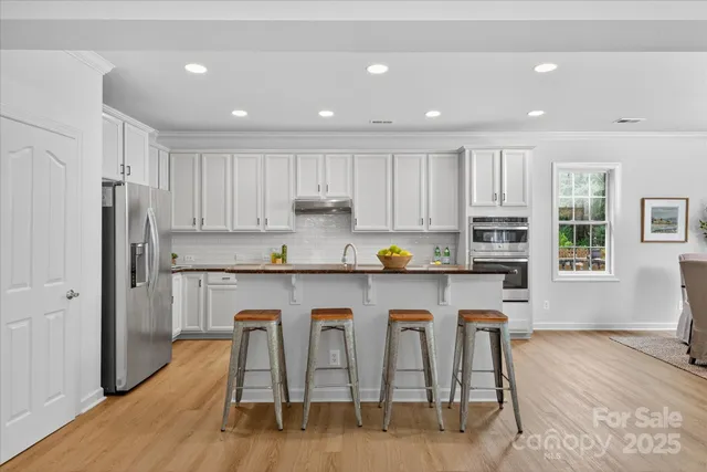 a kitchen with stainless steel appliances granite countertop a white cabinets and wooden floor