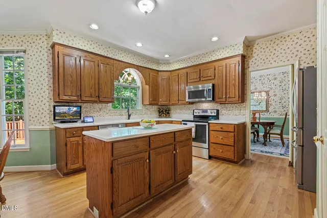 a kitchen with stainless steel appliances granite countertop wooden cabinets a sink dishwasher a stove and a refrigerator with wooden floor