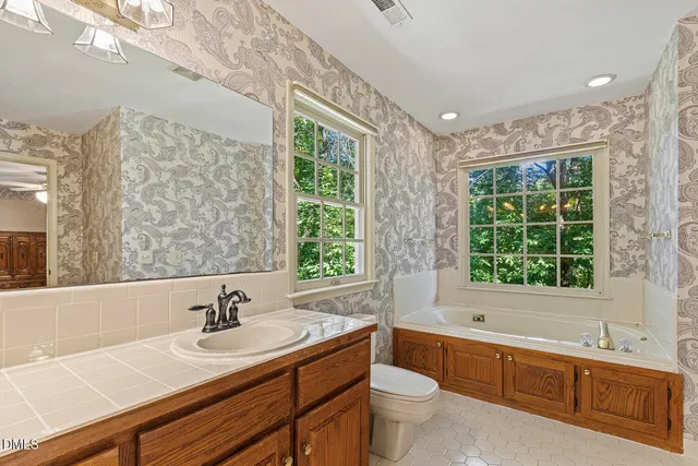 a bathroom with a granite countertop sink mirror bathtub and toilet