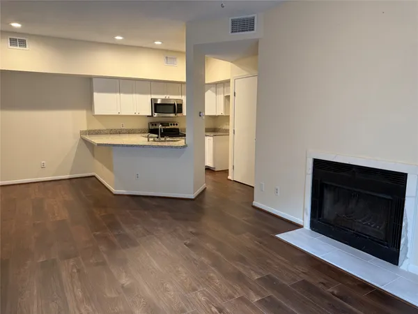 a view of open kitchen with kitchen island a sink wooden floor and a refrigerator