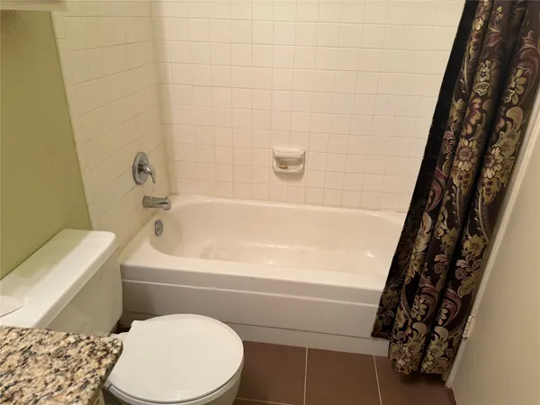 a bathroom with a granite countertop toilet sink and mirror