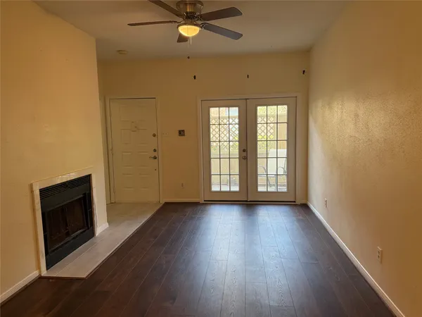 an empty room with wooden floor fan and windows