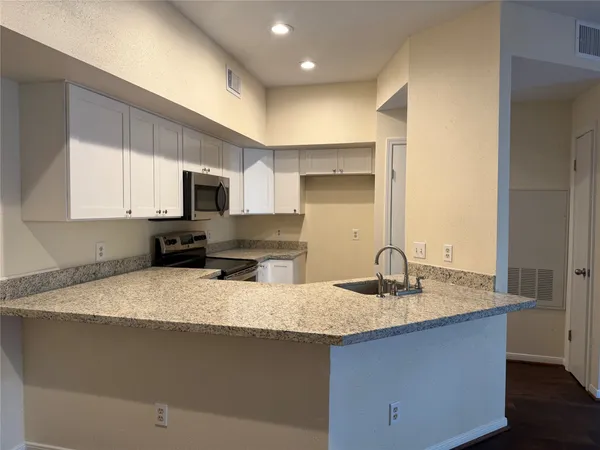 a kitchen with sink a microwave and cabinets