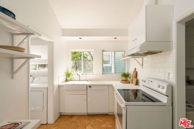 a view of a kitchen with sink and washer dryer