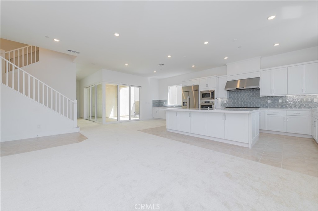 414 Treble Irvine, CA 92618 - Photo 6 of 34 a large white kitchen with kitchen island a sink a center island stainless steel appliances and a refrigerator
