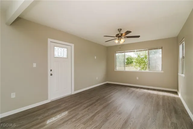 an empty room that has a window and wooden floor