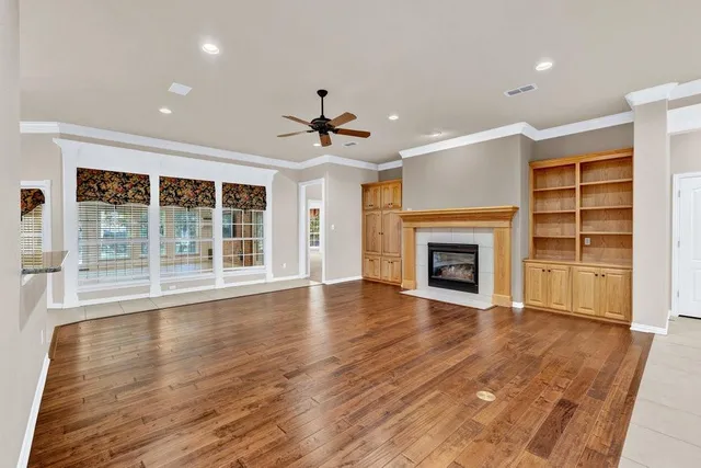 an empty room with wooden floor fireplace and windows