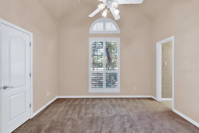 an empty room with a chandelier fan and windows