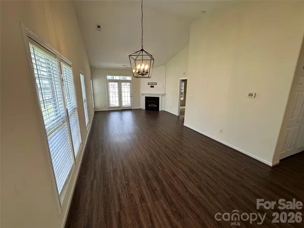 a view of a room with wooden floors fireplace and windows