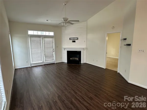 an empty room with wooden floor fireplace and windows