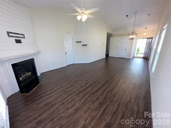 a view of an empty room with wooden floor and a fireplace