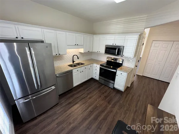 a kitchen with granite countertop a refrigerator and a stove top oven