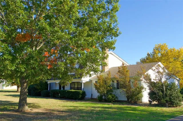 a front view of a house with a garden and trees