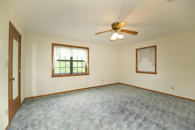 an empty room with chandelier fan and windows