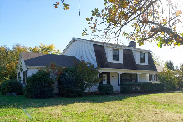 a view of a house with a yard plants and a large tree