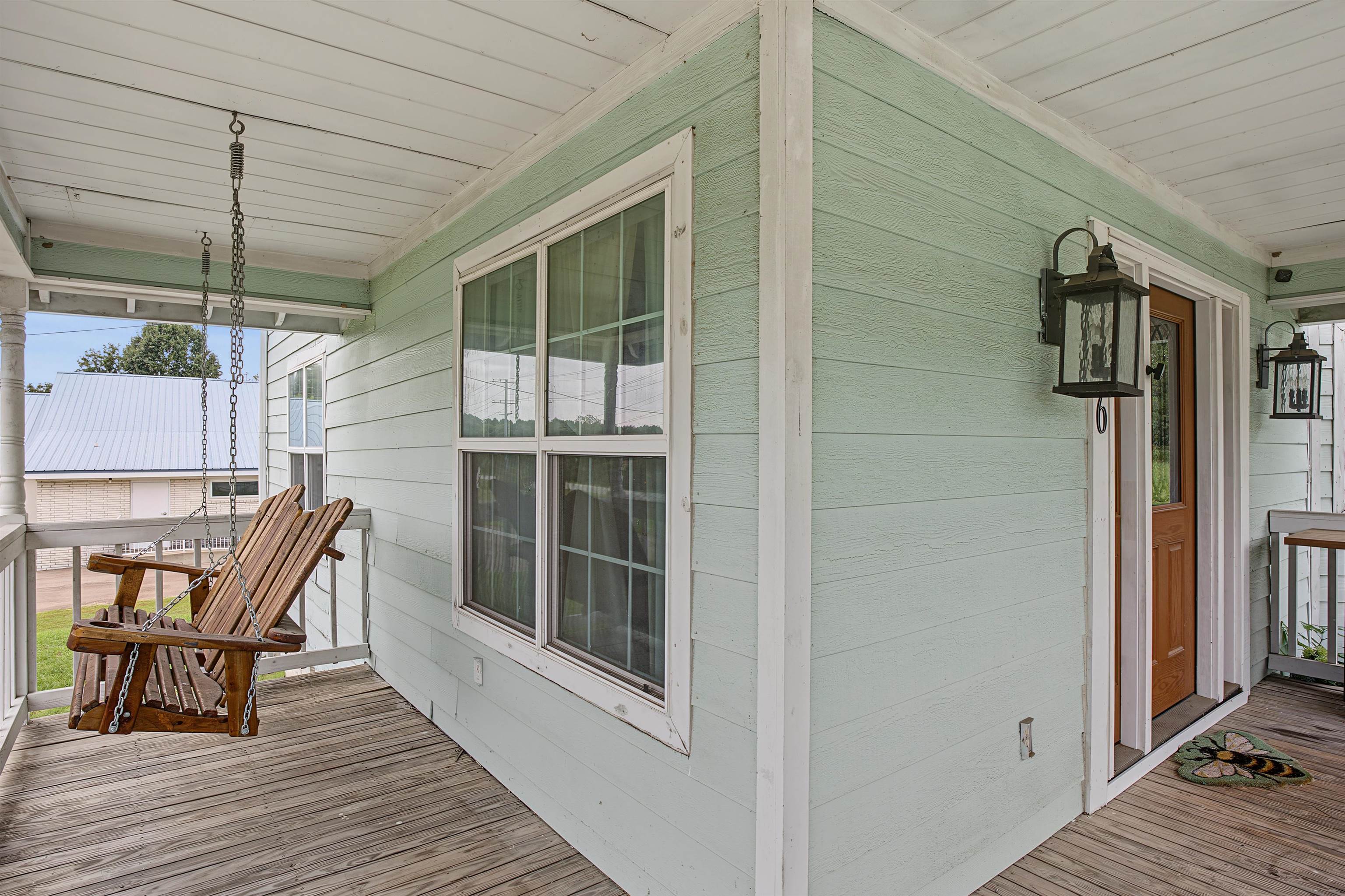 246 Cherryville Road Bells, TN 38006 - Photo 2 of 31 Covered porch with wood-finish flooring, light green siding, white trim, and exterior wall lanterns