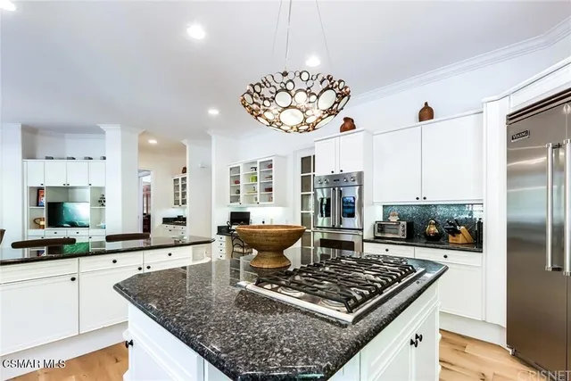 a kitchen with a stove a sink cabinetry a chandelier and kitchen view