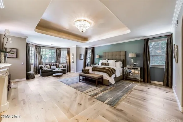 a spacious bedroom with a large bed a fireplace and windows