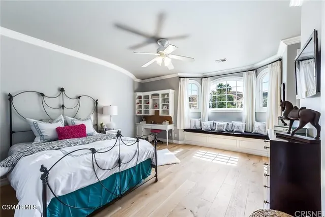 a bedroom with a bed a workstation with bookshelf and a window