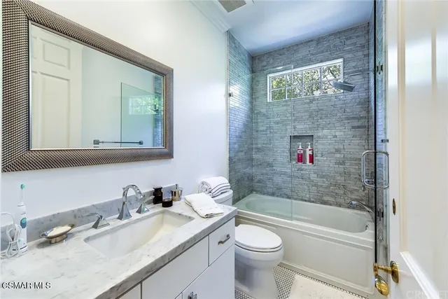 a bathroom with a granite countertop sink a toilet a mirror and shower